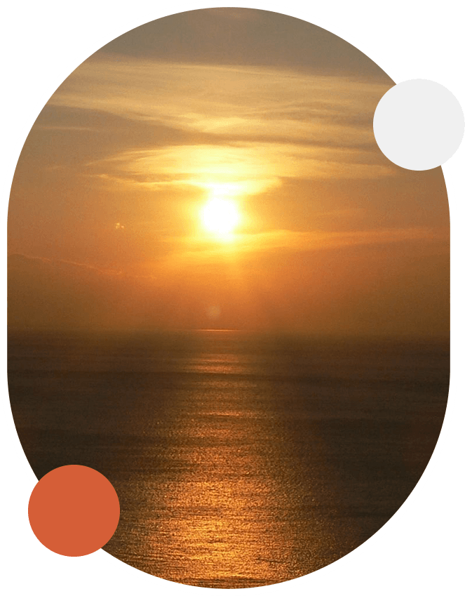 A sunset over the ocean with orange and white circles around it.